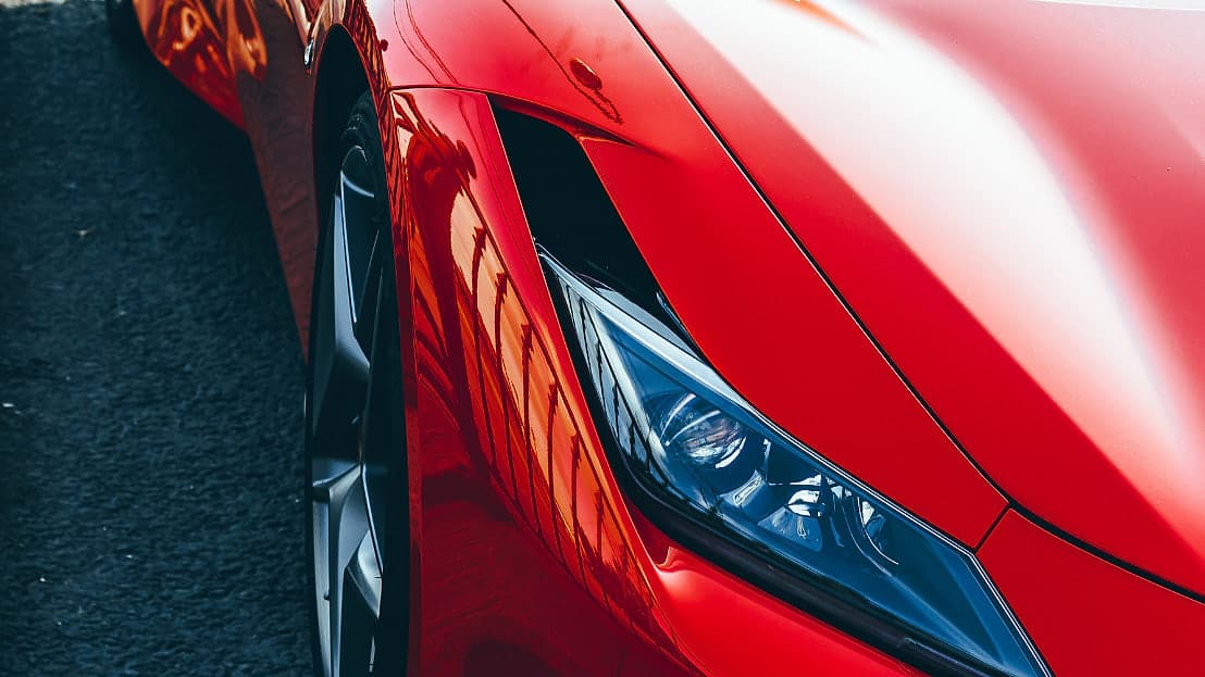 Close detail of the front wing and headlight of a red Ferrari