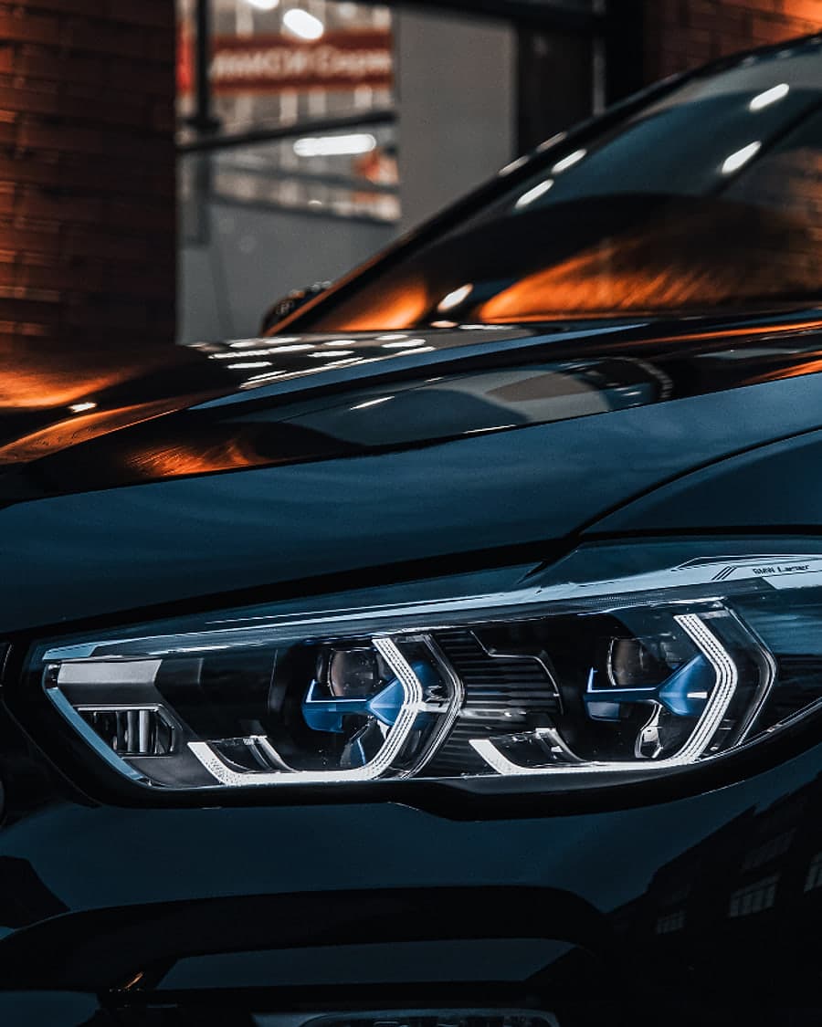 A lit headlight on a dark SUV at night