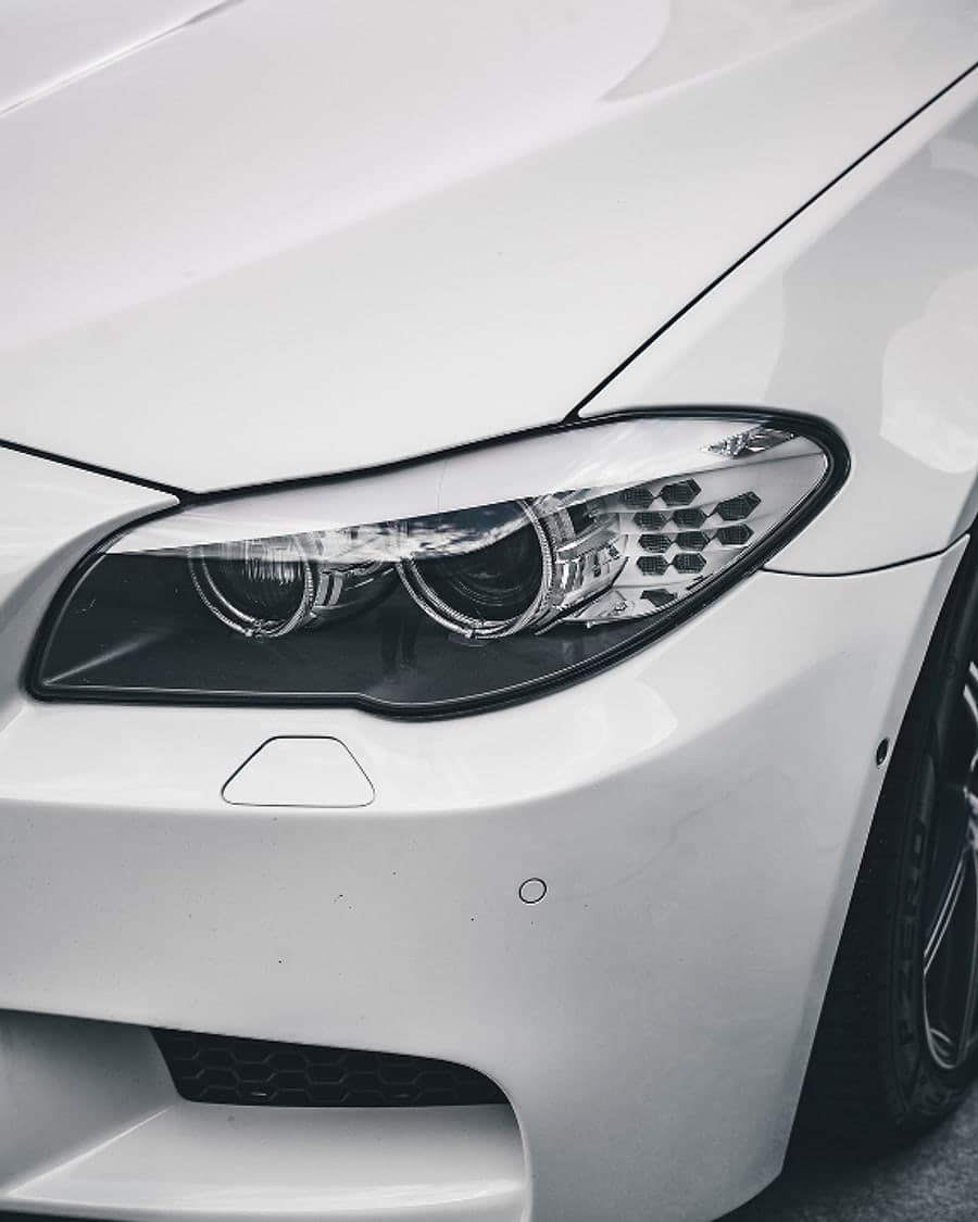 The headlight and front wing of a white saloon in close detail